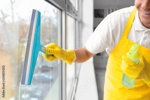 Male janitor cleaning windo...