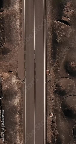 amper car vehicle traveling and driving on a long straight road in scenic volcanic place. Above drone aerial view of people and travel concept. Black sand volcanic ground viewed from vertical view