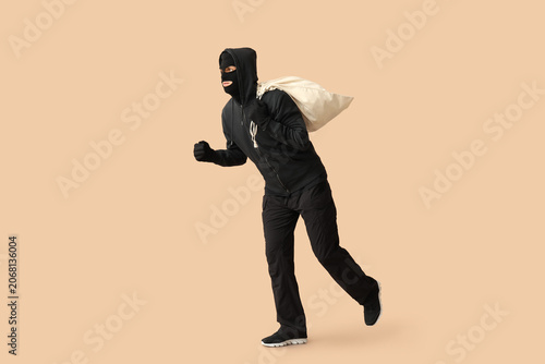 Obraz na płótnie Male thief with bag on beige background