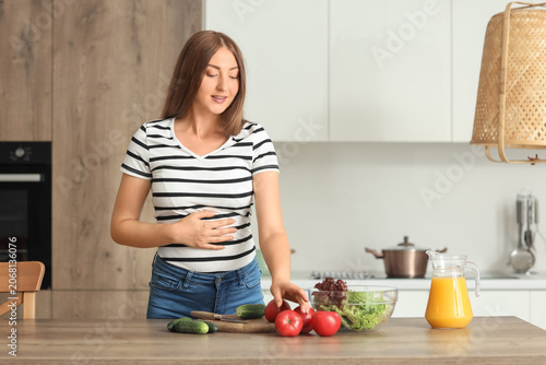 Young pregnant woman cookin...
