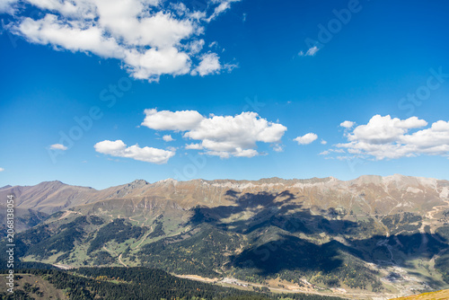 Horizontal panoramic mountain ridges under blue sky and white clouds in Arkhyz Karachay Cherkessia Russia.