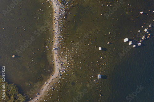 Aerial view of Kuradi saar featuring a rocky spit extending into the shallow coastal waters with scattered boulders and reeds in Kasmu, Laane-Viru County, Estonia.
