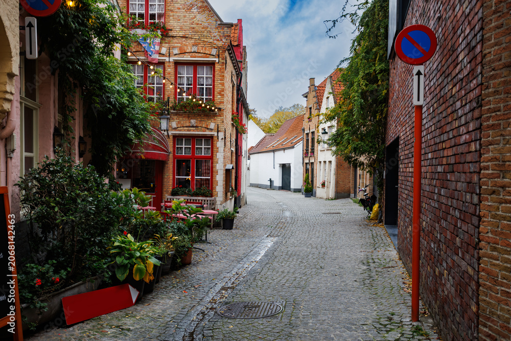 Naklejka premium Cobbled European alleyway street with cafes in Bruges, Belgium