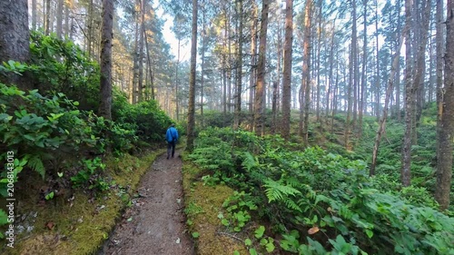 Following Man on Moss Lined Coastal Trail Along the Oregon Coast