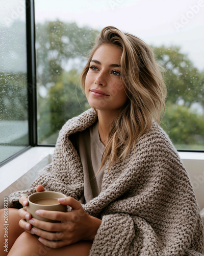 Cozy morning inside with a woman enjoying a warm drink by the window