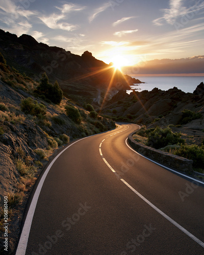 Scenic road curves along the coastline at sunset near the mountains