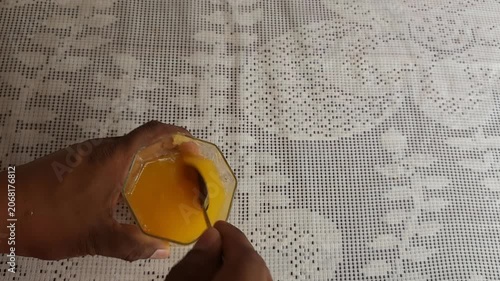 Stirring Turmeric Powder into Fresh Orange Juice with Spoon