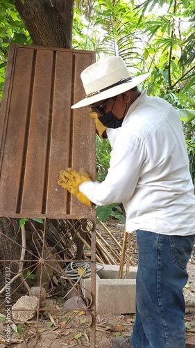 Worker Flipping and Shaking Heavy Rusty Metal Door to Remove Dirt