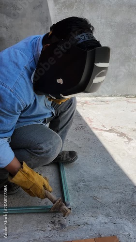 Welder Tapping Metal Pipe Profile with Hammer to Remove Slag