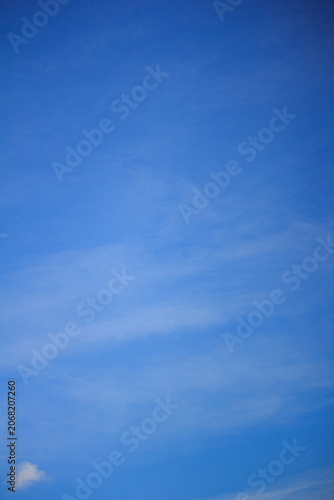 Foto Vertical shot of vibrant blue sky featuring light wispy cirrus clouds and a tiny