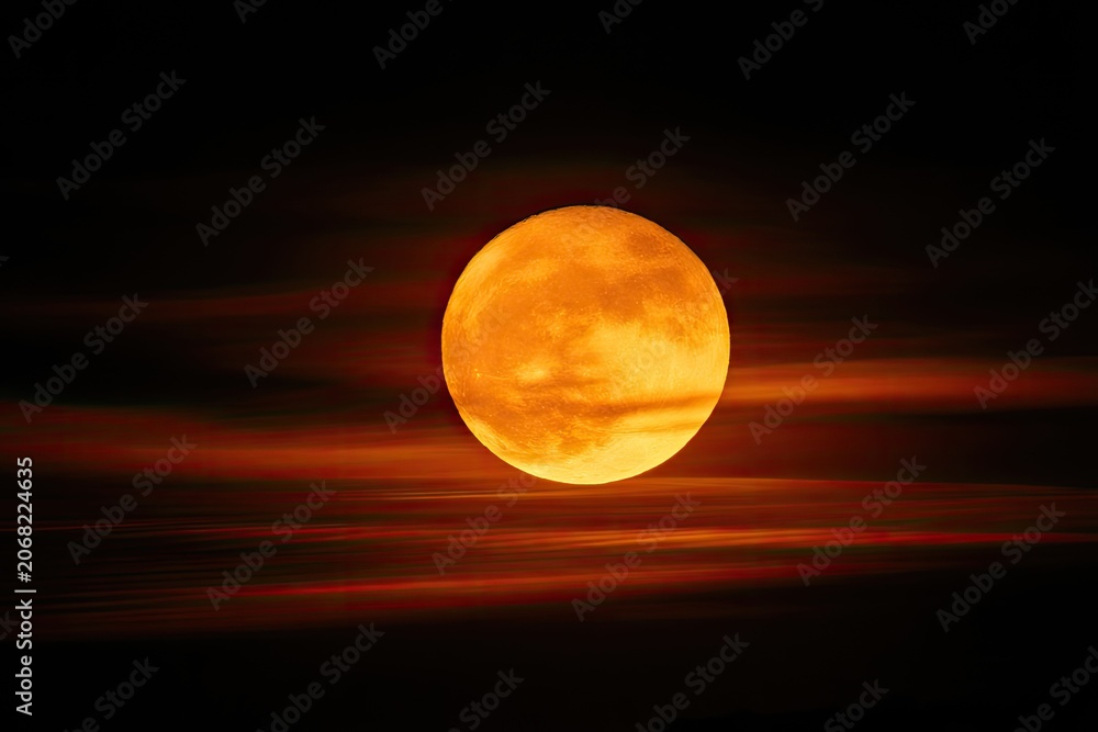 Obraz premium Fiery sun orb glows intensely, partially obscured by streaking red-orange clouds