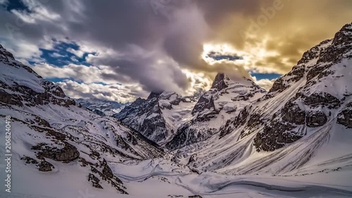 Dramatic clouds hover over majestic snow covered mountain peaks