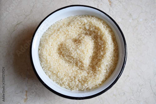 A large enamel bowl of uncooked rice. A heart is drawn on a pile of rice