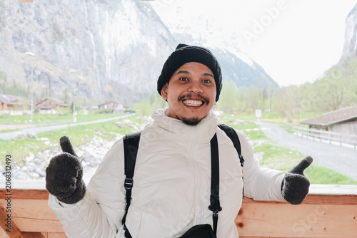 Happy man wearing winter clothes giving thumbs up outdoors.
