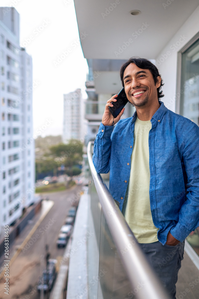 Fototapeta premium Man calling on phone from urban balcony