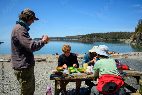 Kayaking group shares lakeside beach lunch | A group of sea kayakers shares a lunch break at a picnic table on a beach on Patterson Island in the Slate Islands, Lake Superior.