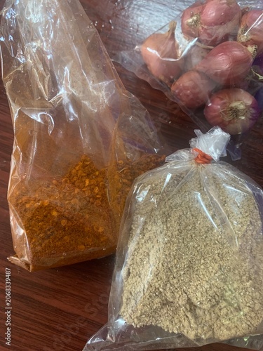 The image shows Thai cooking ingredients: roasted rice, shallots, and chili powder, packaged in plastic bags.