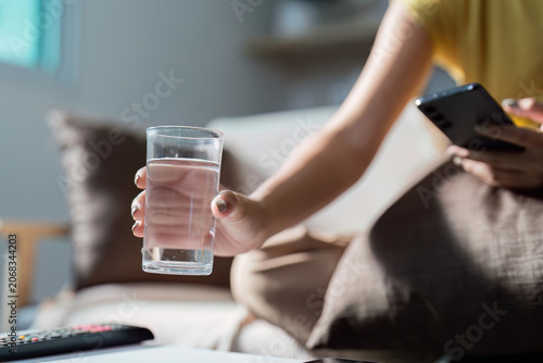 Foto Hand reaching for a glass of water while using smartphone
