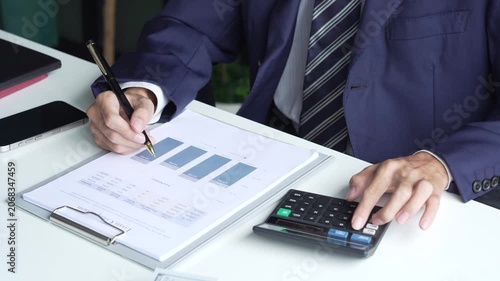 Businessman in suit using calculator and writing on documents