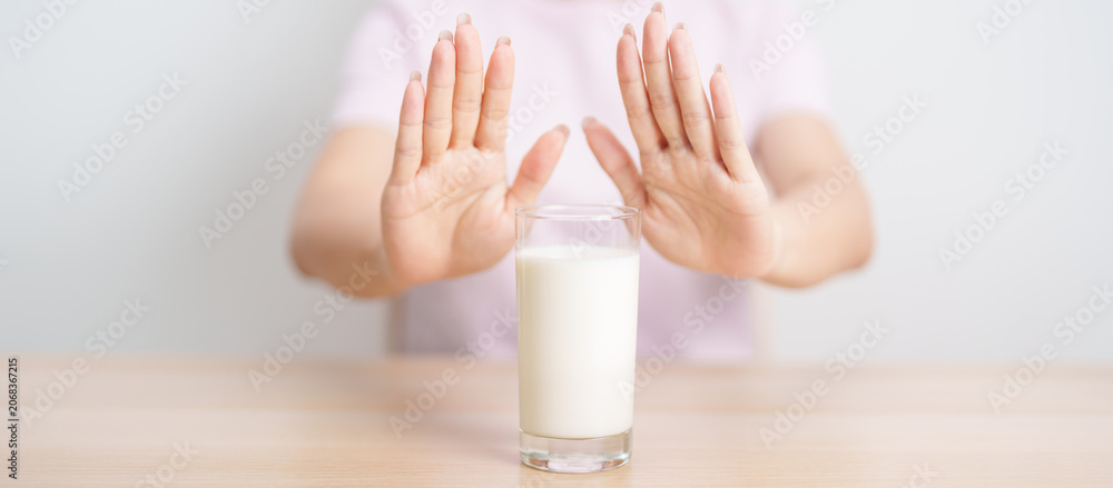Naklejka premium Lactose intolerance and Milk allergy. woman hand stop and refuse Milk, having abdominal cramps and pain when drink Cow Milk. Symptom stomach ache, Dairy intolerant, Nausea, Bloating, Gas and Diarrhea