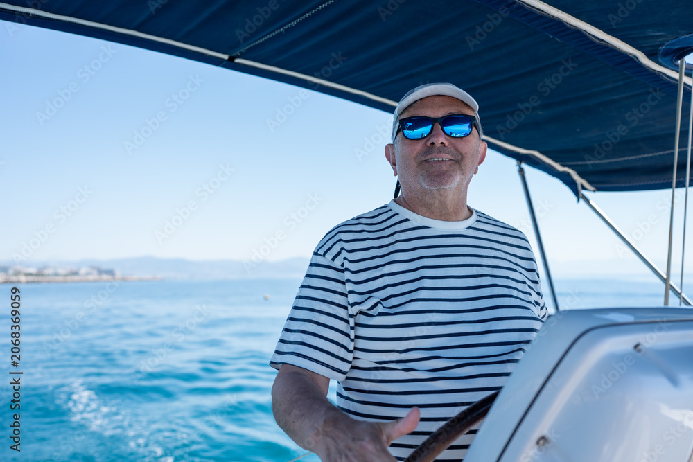 Fototapeta premium Mature man navigating sailboat enjoying summer vacation