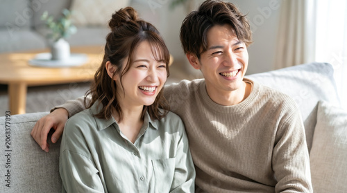リビングのソファで仲良くテレビを見るカップル　自宅デートを楽しむ二人