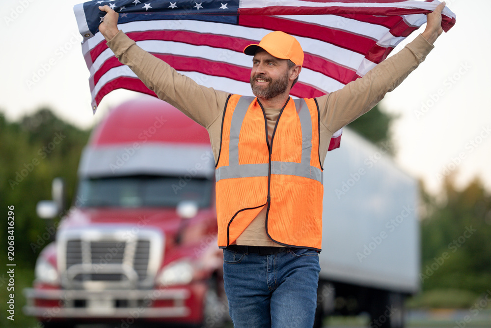 Naklejka premium Truck drivers is a dream job in America. Truck driver hold American flag. A trucking career in the USA. Truck driver country travel. Truck driver best profession in America. Desirable jobs in America.
