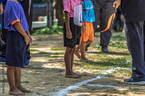 Schoolboy standing with referees checking documents. young schoolboy standing with sports officials and referees holding and checking paper registration documents during outdoor athletic competition.
