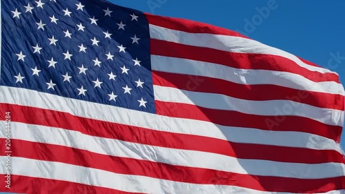 American Flag Waving Proudly A close up shot of the iconic American flag its vibrant red white and blue fabric billowing majestically against a clear bright blue sky