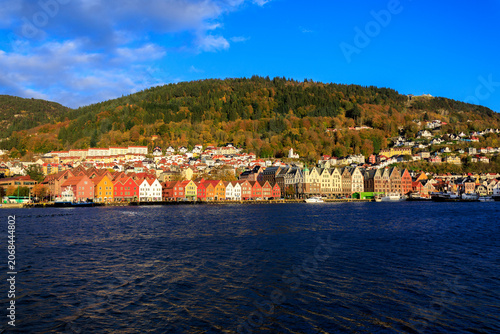 Panorama of Bergen Port with colorful wooden hanseatic buildings of World Heritage Site Bryggen, boats and mountain Fløyen with funicular railway Fløibanen in autumn in Norway