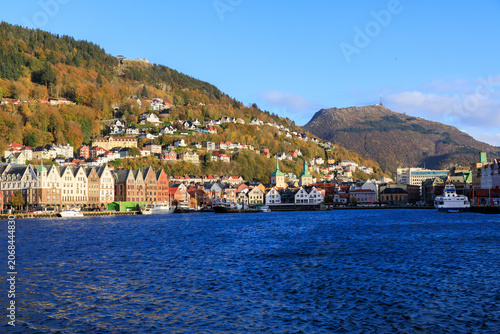 Panorama of Bergen Port with hanseatic buildings of World Heritage Site Bryggen, boats and mountain Fløyen with funicular railway Fløibanen and Ulriken in autumn in Norway