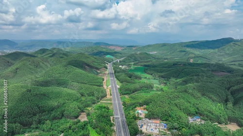 Aerial Highway Through Green Mountain Landscape Under Cloudy Sky