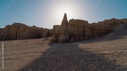 Sunlit layered desert rock formations in an arid canyon landscape