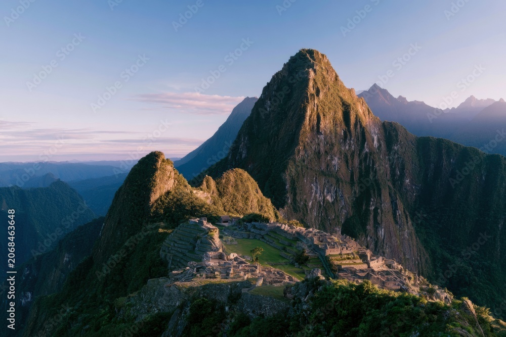 Naklejka premium Ancient South American terraced ruins nestled on a lush mountain saddle under golden morning light for travel and archaeology editorials