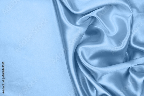 Elegant light blue satin silk fabric texture background with soft folds.