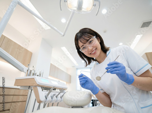 歯科医院で器具を持ち微笑む歯科衛生士の女性