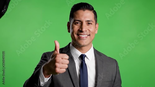 A happy businessman gives a thumbs up on a green screen
