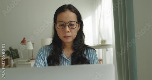 Asian middle woman wear glasses using laptop at home office