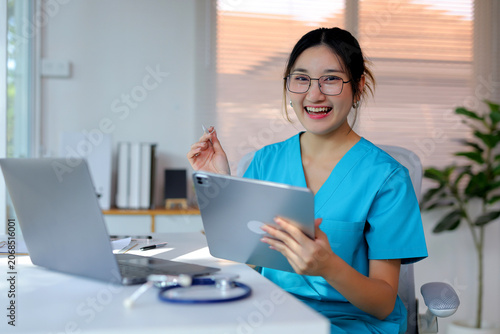 Joyful nurse using tablet and laptop for telemedicine