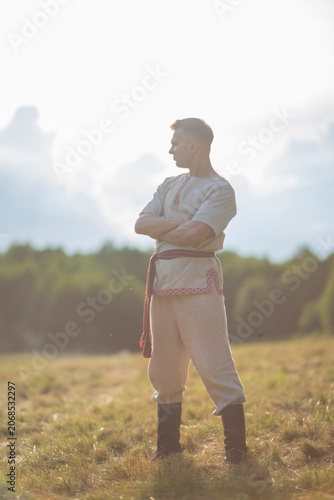 Canvas Print Strong young slavic man with crossed arms posing at summer field with copy space