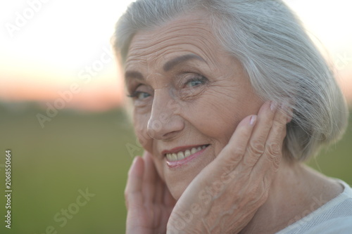 Elderly woman smiling outdoors at sunset