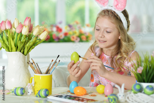 Daughter wearing rabbit ears decorating Easter eggs