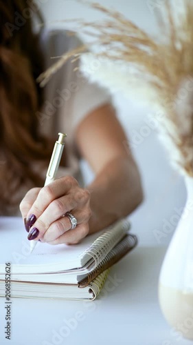 Close up of female hand journaling on desk