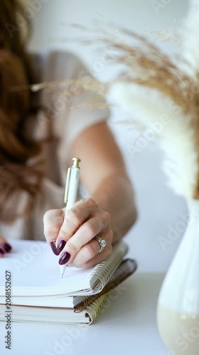 Woman with manicured nails writing in a spiral notebook