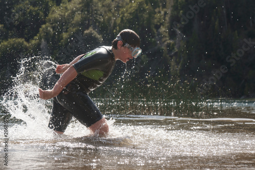 Young boy in a wetsuit splashing in a lake