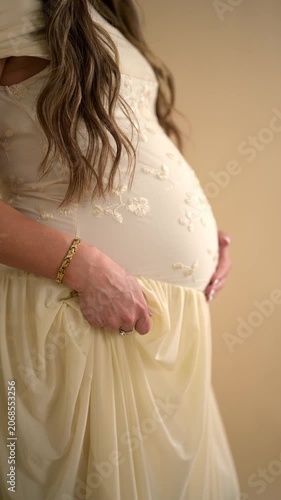 Pregnant woman in dress gently moving her hand across pregnant belly