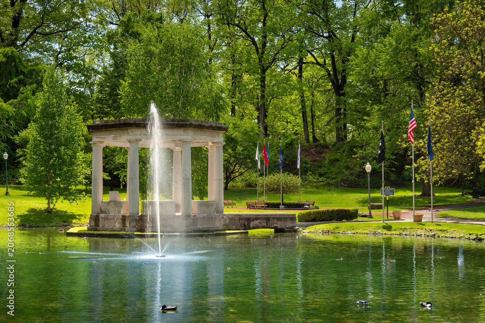 Naklejka premium Classic stone pavilion and a water fountain spraying in a pond