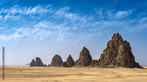 Expansive desert landscape with dramatic rock formations under clear blue sky, natural daylight illumination, f/8.0, arid wilderness scenery 