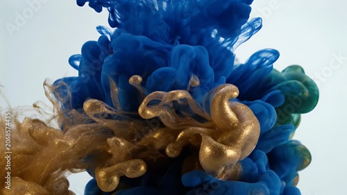 A vibrant blue ink cloud expands in water, contrasted by a golden nozzle, creating an abstract and dynamic visual effect.