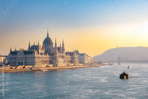 The Hungarian Parliament Building at sunrise with a boat on the Danube River in Budapest, Hungary
